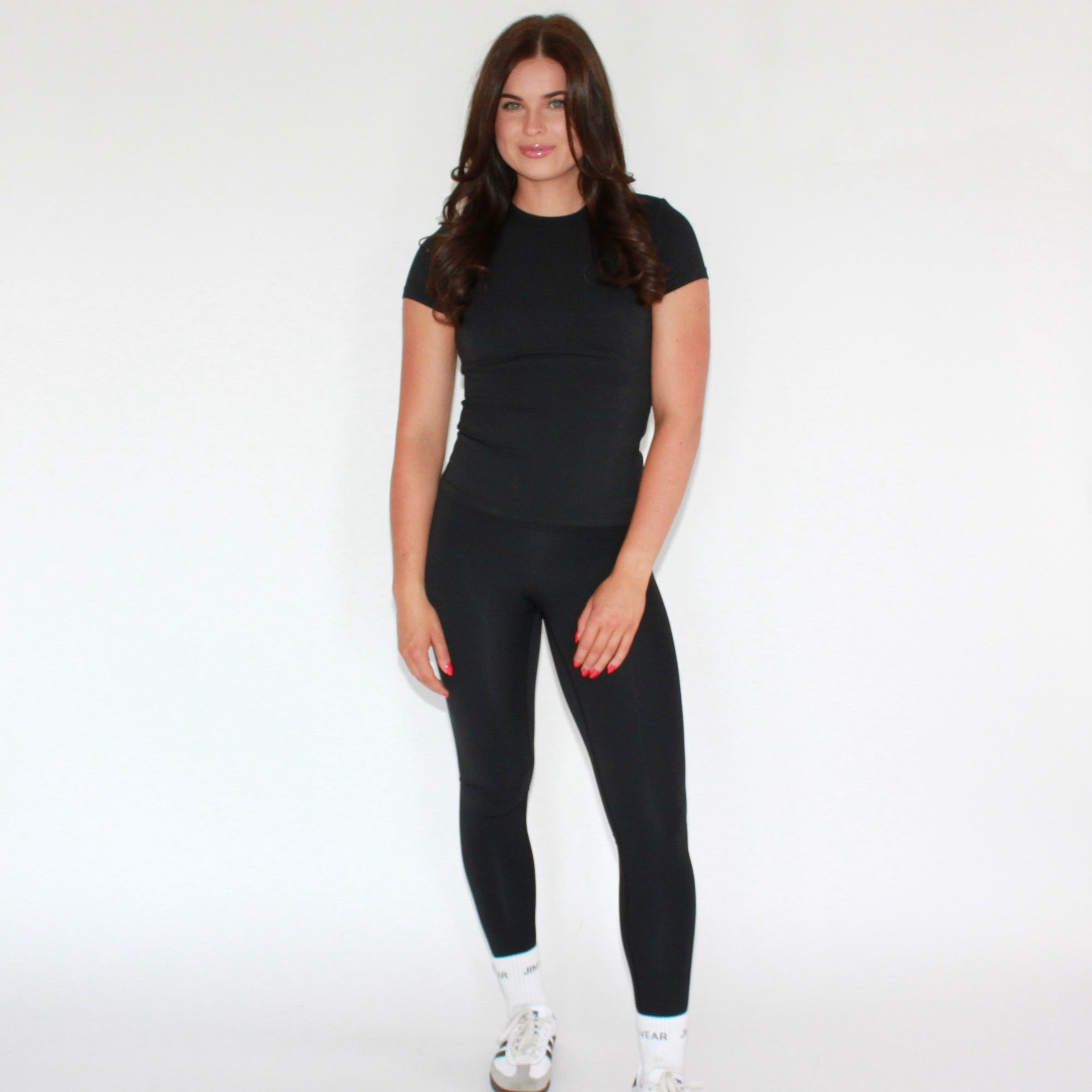 Person wearing a black outfit with white sneakers on a white background